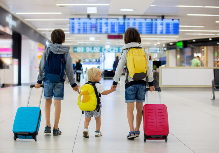 Sweet children, brothers, boys, walking hand in hand at the airport, carrying suitcases and backpacks, family holiday