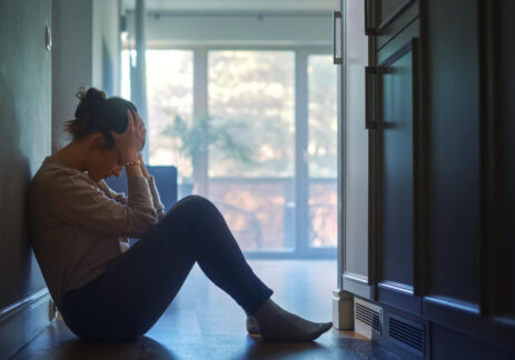 Sad Young Woman Sitting on the Floor In the Hallway of Her Appartment, Covering Face with Hands. Atmosphere of Depression, Trouble in Relationship, Death in the Family. Dramatic Bad News Moment